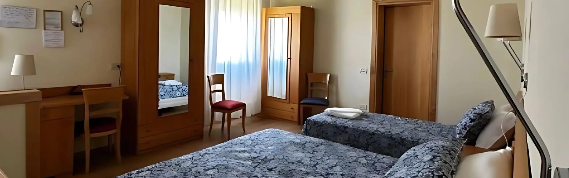 Room with blue bedspreads, desk and wooden wardrobes
