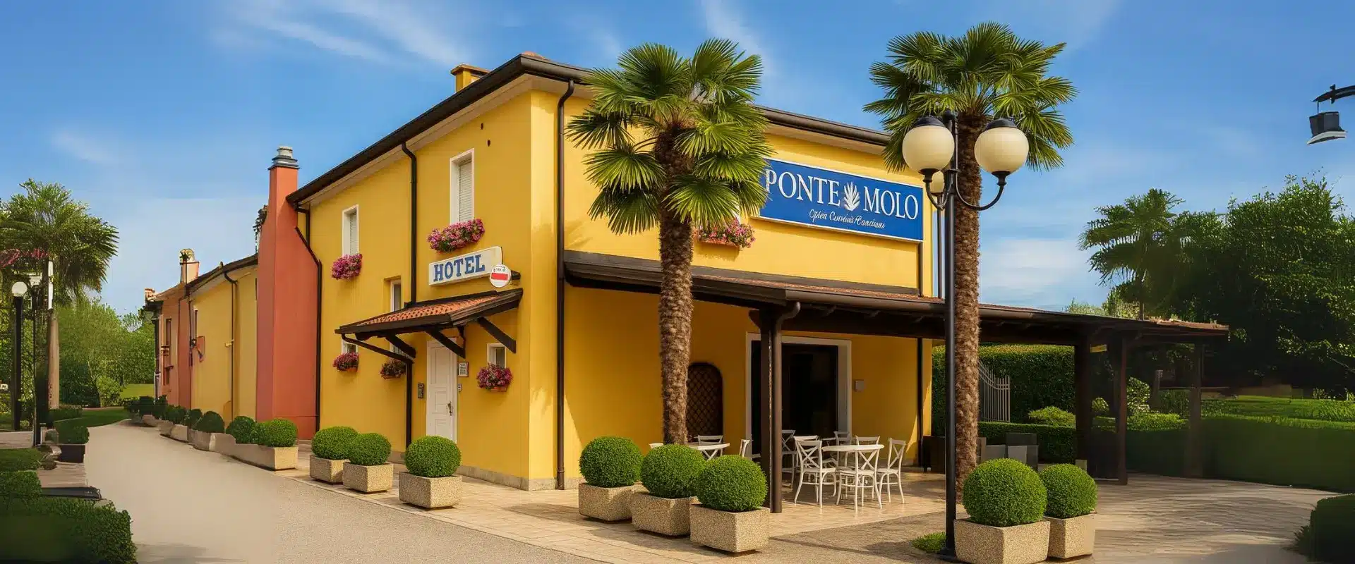 Yellow facade of Ponte Molo, with palm trees and hotel entrance